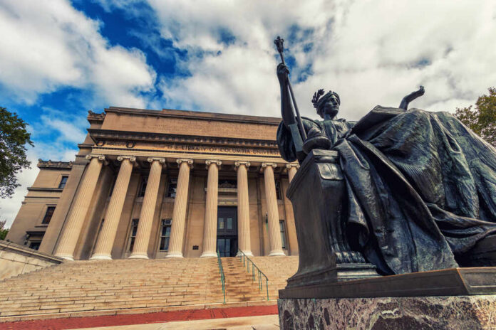 Bronze seated statue before a neoclassical building with tall columns