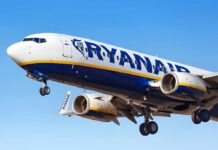 Conflicting Reports Surround Ryanair Emergency Silhouette of a traveler holding a coffee cup and standing next to a suitcase, looking out at an airplane taking off from the airport