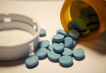 DOJ Crushes Telehealth Pill Mill A handgun, cash, and prescription pills scattered on a surface