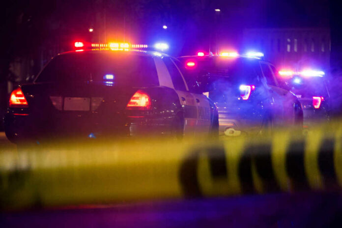 shutterstock1349511497jpg Police cars with flashing lights at a nighttime scene behind crime scene tape