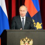 How Russia Preserves Nuclear Retaliation man in suit speaking at a podium with flags behind him