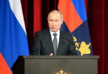 How Russia Preserves Nuclear Retaliation man in suit speaking at a podium with flags behind him