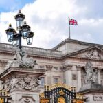 Police Charge Woman After Online Post Buckingham Palace facade with Union Jack flag and ornate gate