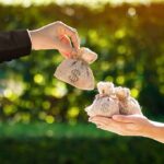 NYC Publishes ‘Hit List’ of the Rich Hands exchanging small burlap money bags outdoors