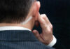 Close-up of a man in a suit with an earpiece, indicating a security role