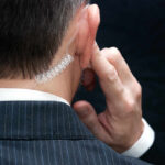 Butler Shooting Report Reveals Major Lapses Close-up of a man in a suit with an earpiece, indicating a security role