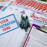 Voter registration table with forms, pens, and informational materials