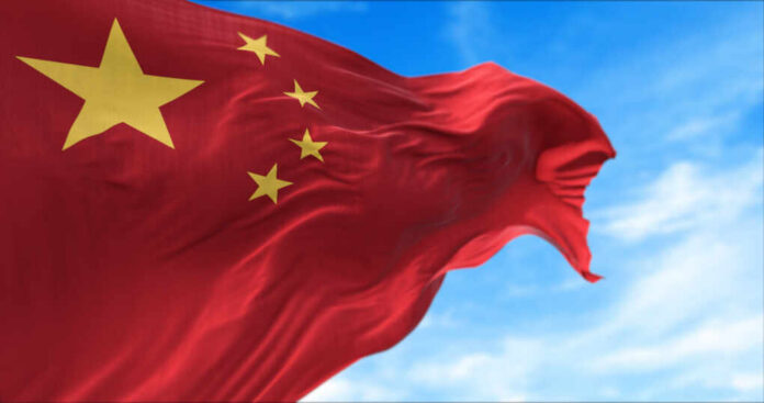 The,National,Flag,Of,People's,Republic,Of,China,Flying,In Waving Chinese flag with five yellow stars against a blue sky