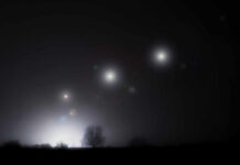 Foggy night landscape with distant lights and silhouetted trees