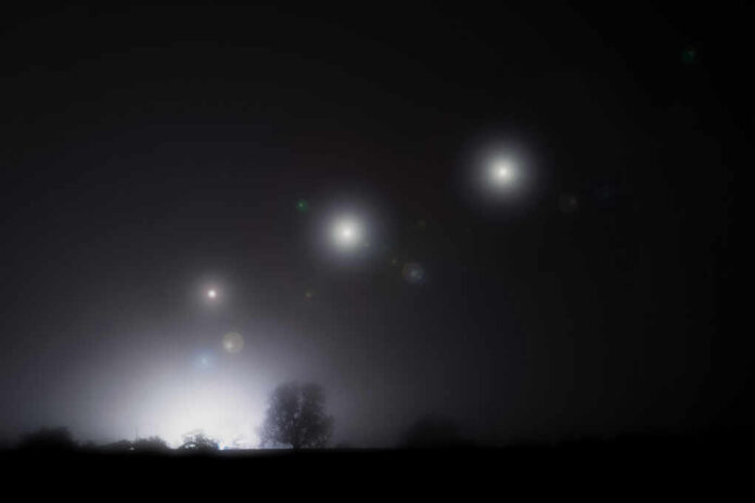 Foggy night landscape with distant lights and silhouetted trees