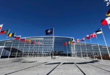 NATO headquarters with member flags in front under a clear blue sky