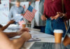 Will Senate Block SAVE America? People participating in a voting event with American flags and paperwork
