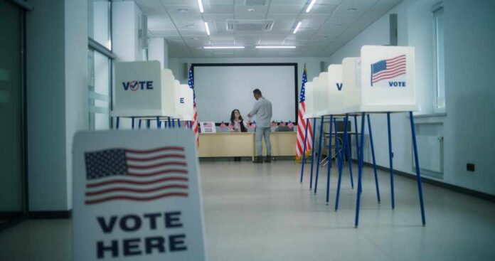 Us,Citizen,,African,American,Male,Voter,Walks,To,Female,Polling Interior of a polling station with voting booths and officials