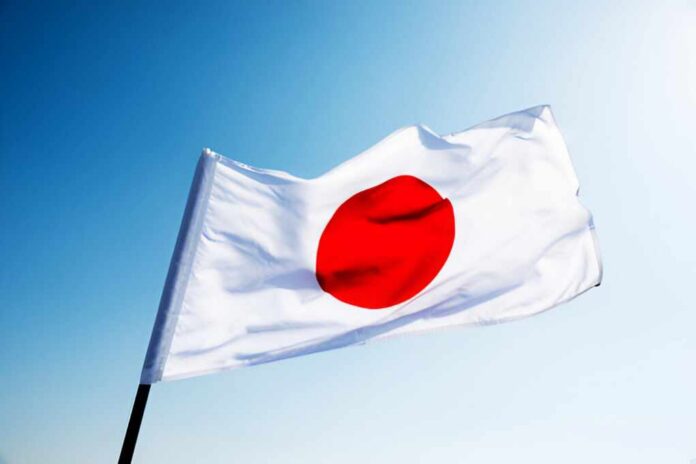 Flag,Of,Japan,Waving,In,The,Wind Japanese flag with a red circle on a white background waving against a blue sky