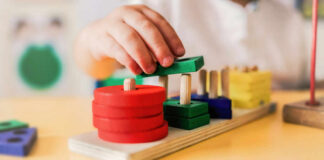 Childs hand stacking colorful wooden blocks