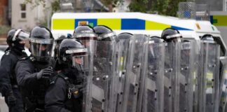 Riot police in formation with shields preparing for crowd control