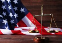 golden balance scale in front of an American flag