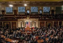 Supreme Court Twist Fuels Redistricting Fury Legislators gather on a chamber floor beneath a large flag