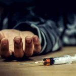 Syringe on table near an outstretched hand