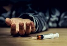 Syringe on table near an outstretched hand
