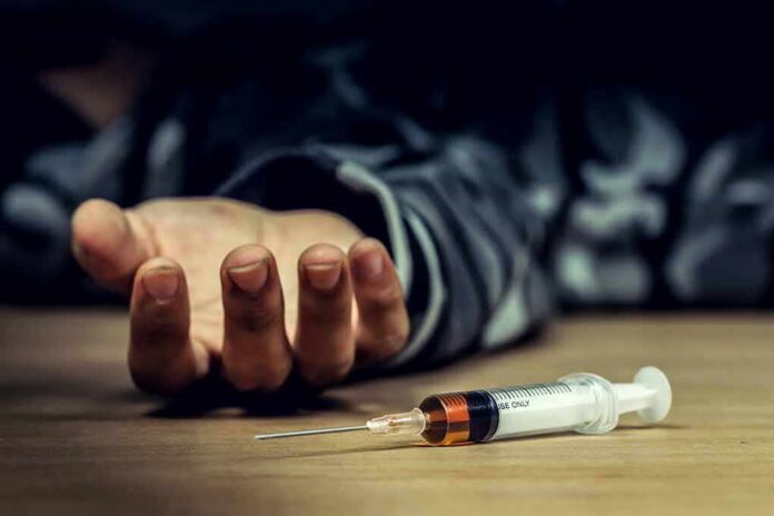 shutterstock_1218461560 Syringe on table near an outstretched hand