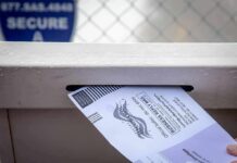 Mail-in ballot being inserted into a secure drop box slot