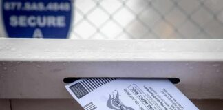 Mail-in ballot being inserted into a secure drop box slot