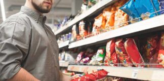 man shopping for snack chips in a grocery aisle