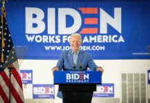 DOJ Task Force Drops Bomb On Biden’s Washington smiling man at podium during campaign event