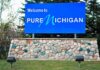 Could El-Sayed’s Auto Plans Cost Michigan? Blue roadside sign on a stone base at a state border