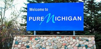 Could El-Sayed’s Auto Plans Cost Michigan? Blue roadside sign on a stone base at a state border