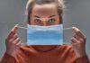 Person holding a blue surgical mask in front of their face