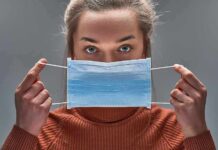 Person holding a blue surgical mask in front of their face