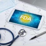 Tablet with FDA on screen amid medical tools and ECG charts