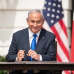 Israel Builds Strategic Alliance Network Man in suit seated at a signing table