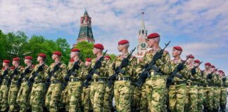Soldiers in camouflage uniforms march in formation with rifles