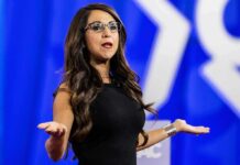 Woman speaking on stage with arms outstretched