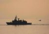 Insurance Panic Over Iran Lane naval ship silhouette at sea during sunset