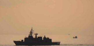 Insurance Panic Over Iran Lane naval ship silhouette at sea during sunset