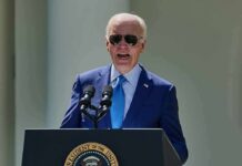 man in blue suit speaking at a podium with presidential seal