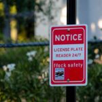 Red notice sign on a black pole in a leafy outdoor area
