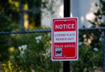 Glitch Turns Highway Stop Dangerous Red notice sign on a black pole in a leafy outdoor area