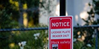 Red notice sign on a black pole in a leafy outdoor area