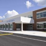 Peeping Scandal Engulfs School Boss Modern school building with large windows and a clear sky