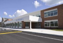 Peeping Scandal Engulfs School Boss Modern school building with large windows and a clear sky