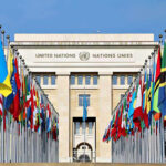 UN Showdown Week Begins United Nations building with numerous national flags outside.