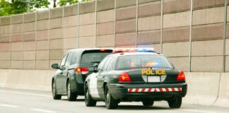 Police car with flashing lights stops a minivan on highway