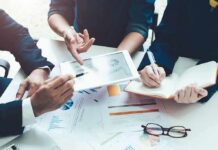 Panic Moves As Startups Flee Business meeting with hands pointing at tablet and taking notes