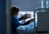 Canada’s Assisted Death Numbers Hit New High Patient in hospital bed with visitor holding their hand