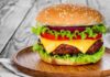 Cheeseburger with lettuce, tomato, and onion on a wooden plate